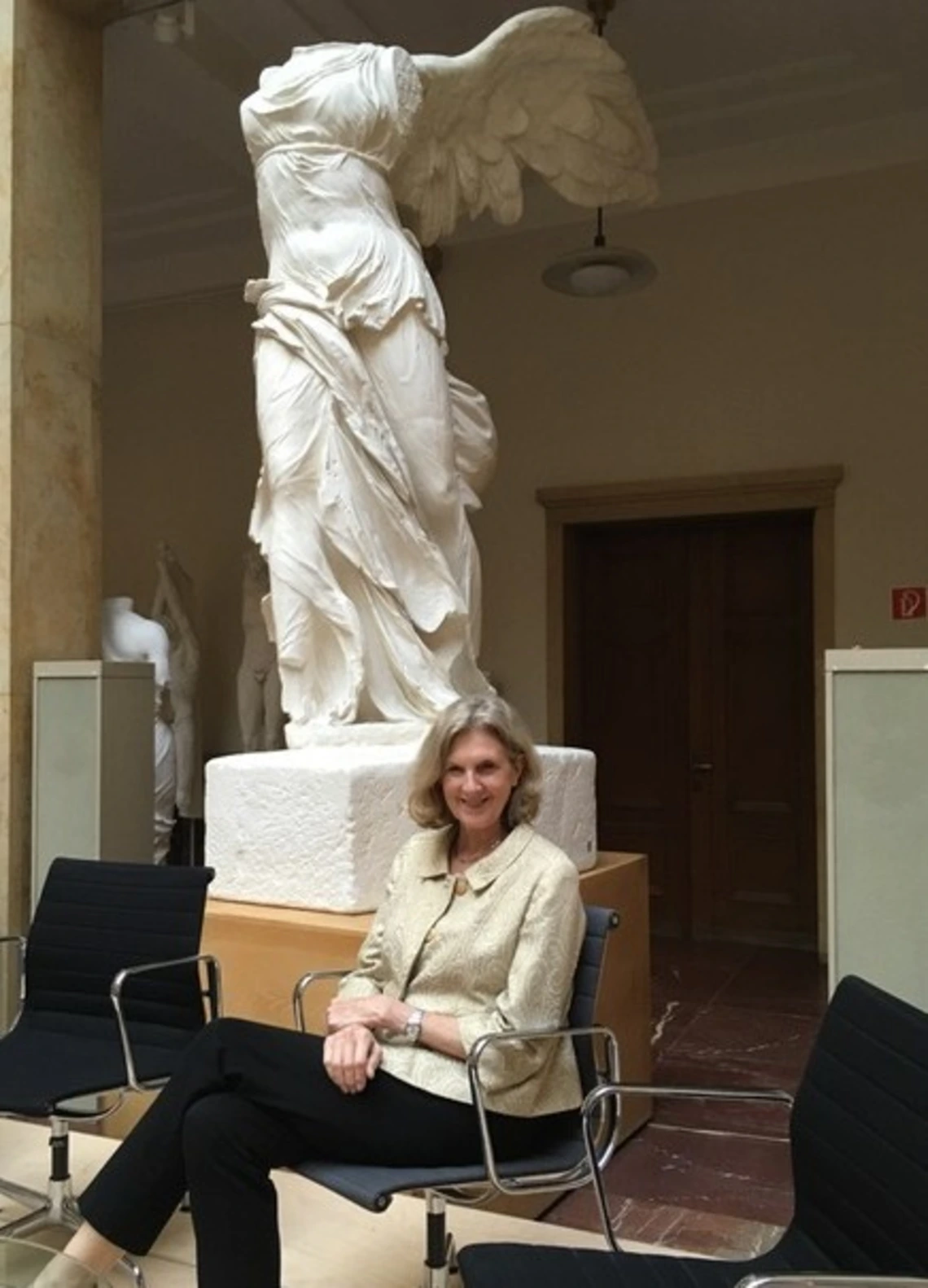 Dr. Irene Romano sits smiling in front of a piece of statuary