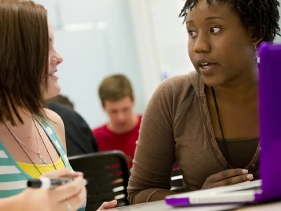 Two students talking at their desk.