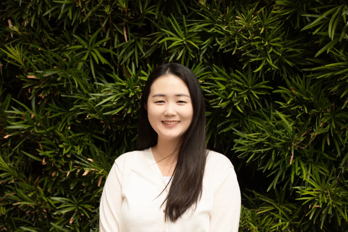 Chaelin Kwon Headshot against a background of slim-leafed green plants